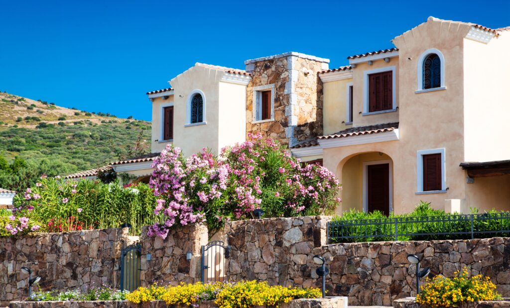 Mediterrane Villa mit steinernen Akzenten, Rundbogenfenstern, üppigem Garten und Hanglage; Nießbrauchrecht sorgt für nachhaltigen Genuss.